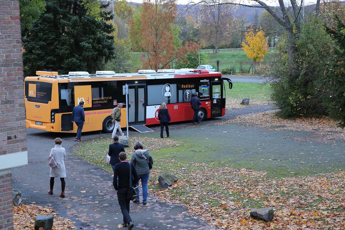 Mehrere Patienten laufen auf den Medibus zu.